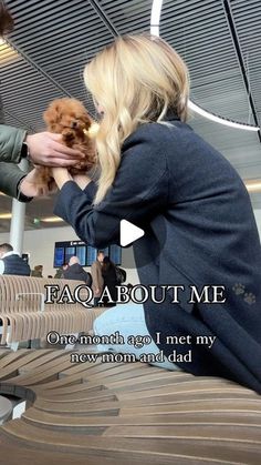 a woman holding a small dog in her lap while sitting on a bench at an airport