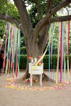 an outdoor ceremony with streamers and confetti on the ground under a tree