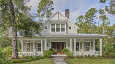 a white house surrounded by trees and grass with a walkway leading to the front door