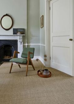 a chair sitting in front of a fire place next to a doorway with a mirror on the wall