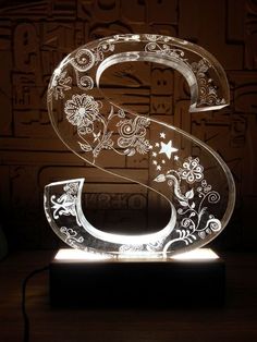 the illuminated number six with flowers and stars is shown on a wooden table in front of a