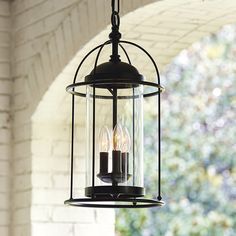 a light fixture hanging from the ceiling in front of a brick wall and arched doorway