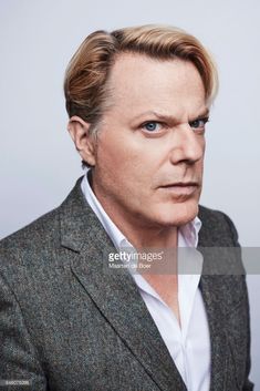 a man in a suit and white shirt looking at the camera with an intense look on his face