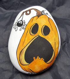 a painted rock with a dog's face on it and a spider in the background