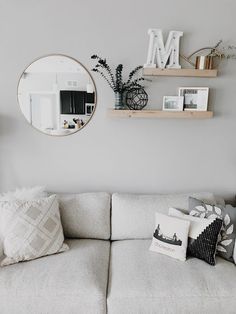 a living room filled with furniture and decor on top of a white couch under a round mirror