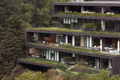 an apartment building with balconies and plants on the top floor is surrounded by greenery