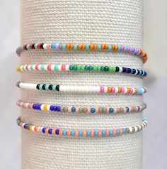 Introducing a beautiful set of random seed bead bracelets, meticulously handmade with love. Inspired by the 'bestseller' summer seed bead bracelets, these bracelets feature tiny beads measuring just 2mm. Perfect for any occasion, these delicate bracelets make a wonderful gift. Embrace the joy of layering bracelets without the heavy or bulky feeling - you'll hardly even notice you're wearing them! The average woman's wrist size is around 7 in When orders are prepared I choose completely random bracelets for each set. If you would like a certain pattern or particular colors please leave a note! :) These are made with high quality elastic bead cord for a flexible but strong fit. By default, your order will either be enclosed in a jewelry bag or on a logo card with a clear resealable envelope Heishi Beaded Bracelets For Everyday Summer Wear, Everyday Heishi Beads Bracelet For Summer, White Stackable Friendship Bracelets For Summer, White Minimalist Beaded Bracelets For Summer, Minimalist White Beaded Bracelets For Summer, Adjustable Beaded Bracelets For Jewelry Making In Summer, Everyday Heishi Beads Bracelets For Summer, Minimalist Round Bead Bracelets For Beach, Minimalist Round Beads Bracelets For Beach