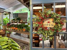 an open sign hanging from the side of a building next to a bunch of vegetables