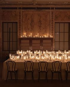 a long table with many lit candles on it and chairs in front of the table