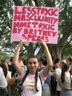 a woman holding up a sign in front of a crowd