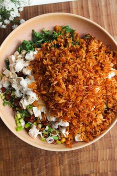 a bowl filled with rice and vegetables on top of a wooden table