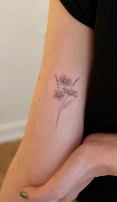 a woman's arm with a small flower tattoo on the left side of her arm