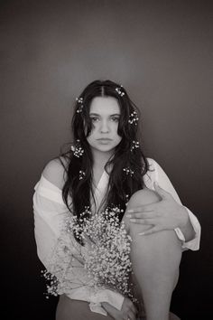 black and white photograph of a woman with flowers in her hair sitting on the floor