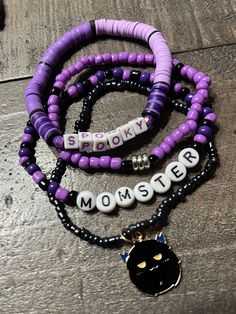 Listing includes stack of 4 Halloween themed bracelets shown in the photo. Bracelet 1 is black and purple Heishi clay beads that says SPOOKY in purple lettering Bracelet 2 is 3mm black and purple seed beads with silver spacers Bracelet 3 is made of black and purple 3mm seed beads that says MOMSTER in black lettering  Bracelet 4 is blackish 2mm seed beads with a gold metal black colored MOMSTER charm Handmade with sturdy, quality elastic These bracelets make PERFECT GIFTS for anyone special!  Siz Purple Beaded Bracelets With Black Beads As A Gift, Handmade Black Heishi Beads Stretch Bracelet, Purple Heishi Beads Bracelet With Spacer Beads, Purple Heishi Beaded Bracelets With Letter Beads, Purple Heishi Beads Bracelet With Letter Beads, Halloween Beaded Bracelet, Purple Gemstone Jewelry, Themed Bracelets, Black Spinel Bracelet