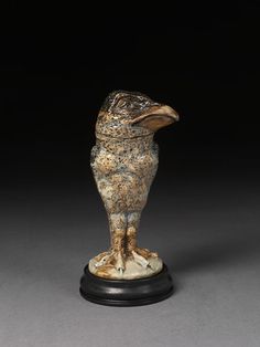 an antique figurine of a bird on a stand