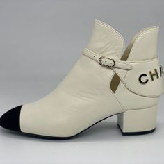 Chanel 2021 (21a Season) Ivory Lambskin Leather Booties Have A Black Velvet Cap Toe And A Goldtone Chanel Signature On The Back. Chanel Embossed Buckle. 1.5" Leather Covered Block Heel. Padded Leather Insole. Leather Sole. Shaft: 4.5". Made In Italy. Designer Color: Ivory/Black. Size: 37 Eu (Insole Measures Approx. 9.5".) Typically Chanel Shoes Run Small. Brand New With The Box And A Dust Bag.