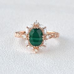 a close up of a ring with a green stone in the middle and white diamonds around it