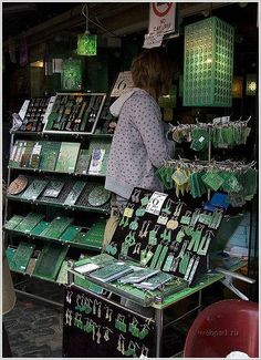 a woman standing in front of a green and white display case filled with cards, magnets and other items