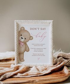 a teddy bear with a pink bow on its neck is next to a sign that says, don't say baby