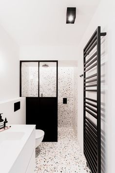 a bathroom with black and white decor on the walls, floor, and shower stall