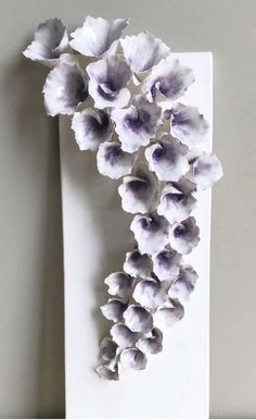 an arrangement of flowers is displayed on a wall