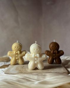 three small candles sitting on top of a white cloth covered table next to each other