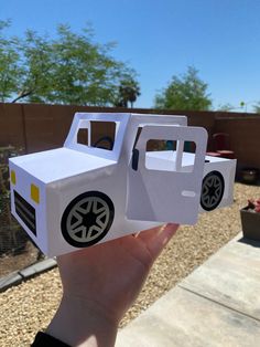 someone is holding up a paper model of a truck in the shape of a car