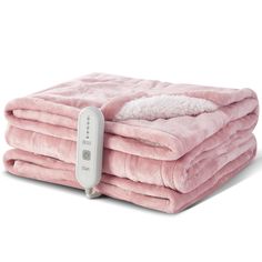 the heated blanket is pink with white fur on it and has a remote control in front of it