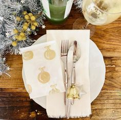 a place setting with silverware and napkins on a wooden table next to christmas decorations