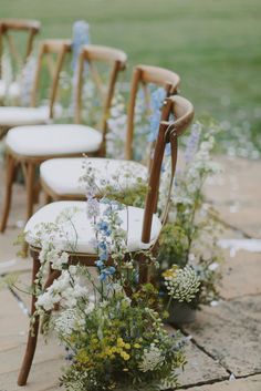 the chairs are lined up with flowers and greenery on each chair, along with other decorations