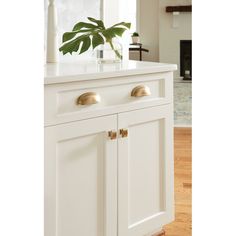 a white kitchen island with brass handles and knobs