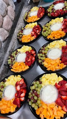 several trays filled with different types of fruit and cheese on top of each other