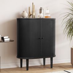 a black cabinet sitting next to a table with vases and books on top of it