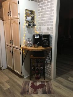 a kitchen area with a counter, refrigerator and coffee pot on the floor in front of it