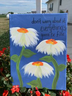 a painted sign with flowers in front of a house