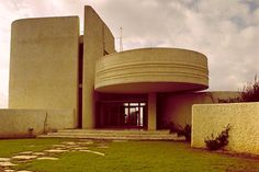 a large building with a clock on the side of it's face and grass in front of it