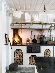 a stove top oven sitting inside of a kitchen next to a firewood log rack