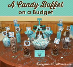 a candy buffet on a table with blue and white candies in glass vases