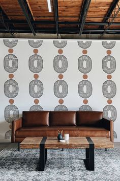 a leather couch sitting in front of a wall with circles on it and a wooden coffee table