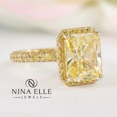 a fancy yellow diamond ring on a white surface