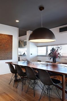 a dining room table with chairs and a large painting on the wall in front of it