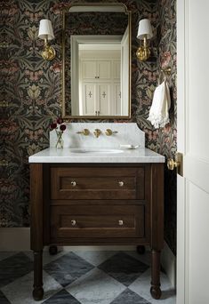 a bathroom vanity with a mirror above it and two lights on the wall next to it