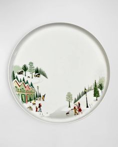 a white plate with a christmas scene painted on the front and side, along with people walking in the snow