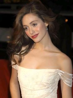 a woman in a white dress posing for the camera with her hair blowing in the wind