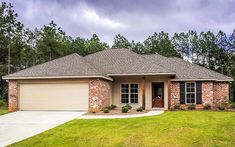 a brick house with green grass and trees in the background