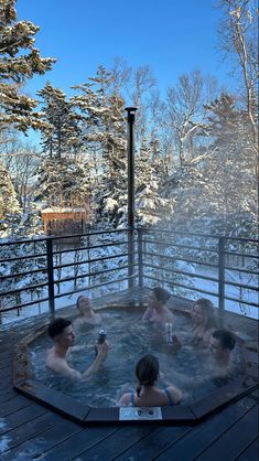 four people sitting in a hot tub with snow on the ground