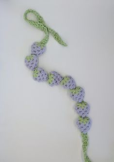 a crocheted piece of cloth with flowers on it and a green string attached to the end