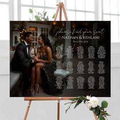 a couple sitting on a bench in front of a wedding seating chart with flowers and greenery