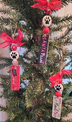 a christmas tree decorated with red ribbon and ornaments for the dog's paw print