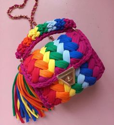 a multicolored bag with a chain attached to it on a pink surface,